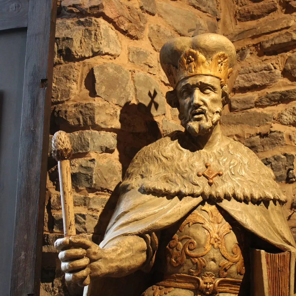 Buste en bois sculpté et peint de Charlemagne en empereur du Saint-Empire romain germanique tenant un sceptre et un recueil de capitulaires, exposé dans la salle des Chevaliers du château de Reinhardstein.