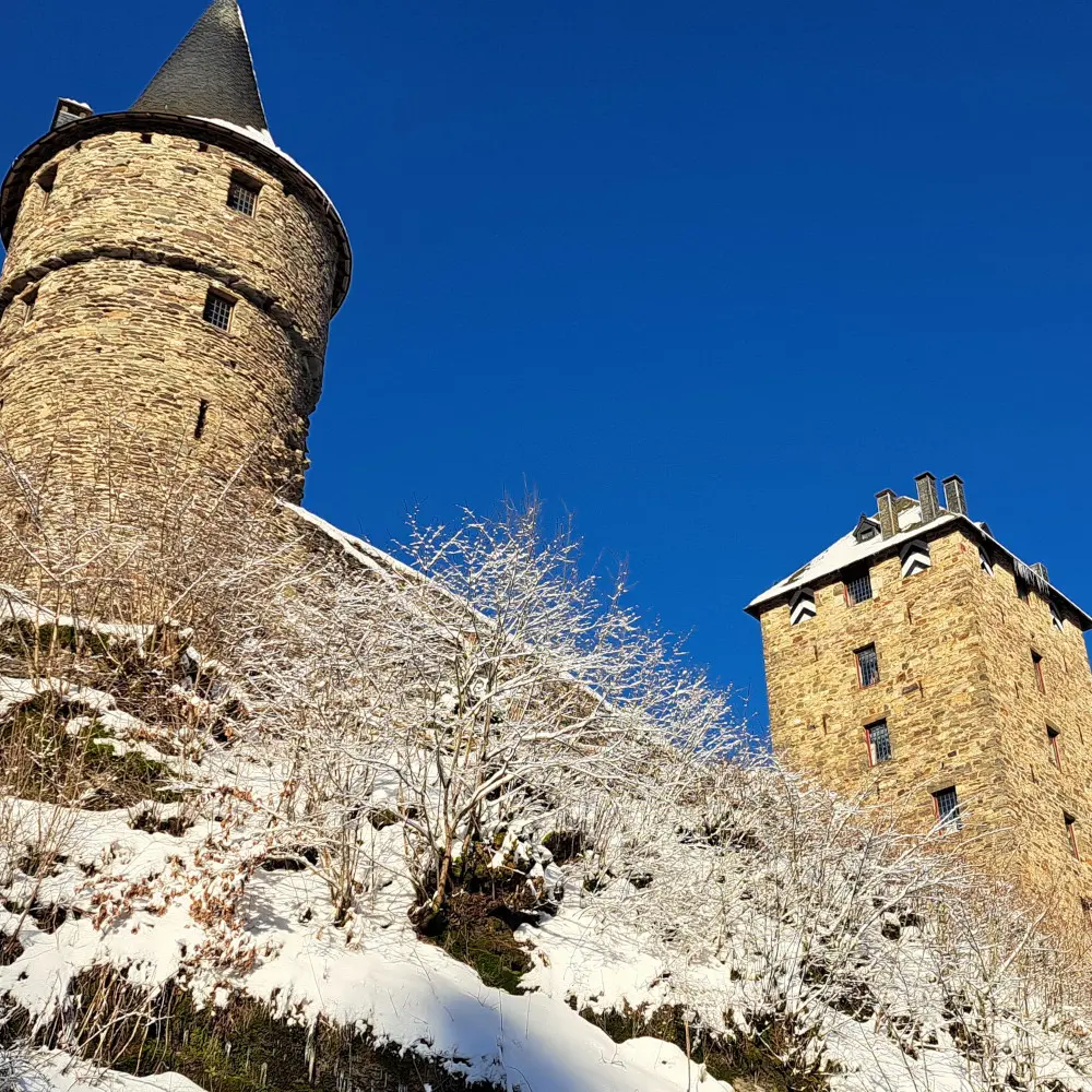 Vue en contre-plongée du château de Reinharstein en hiver, perché au sommet de l’à-pic de 60 mètres qui le protège au Sud et à l’Ouest, avec la tour Salamandre à gauche et le donjon à droite.