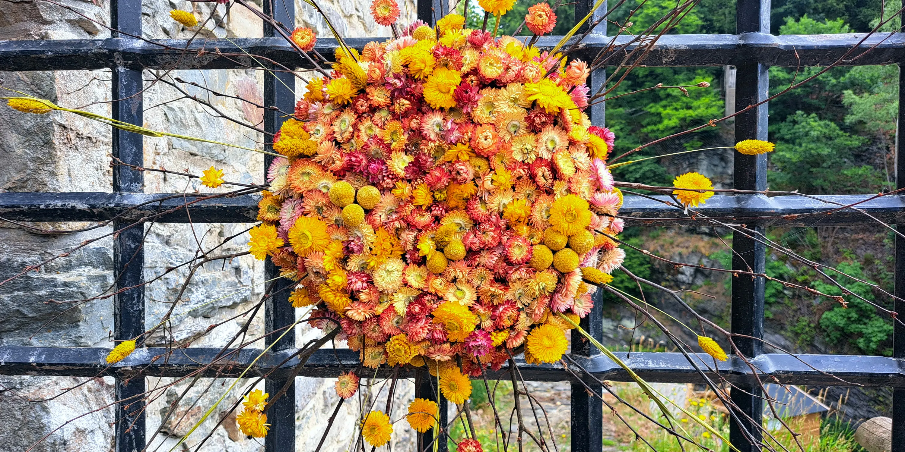 Composition florale installée sur les grilles du château de Reinhardstein lors de l’événement Castelflora en juillet 2025.